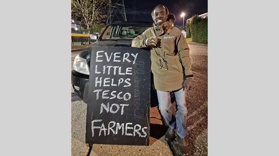Flavian Obeiro protests outside Tesco depot with sign Every Little Helps Tesco Not Farmers